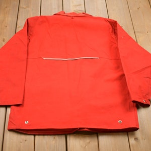 May include: A red long-sleeved jacket with a zipper on the back and silver buttons.