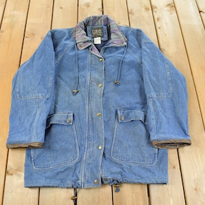 May include: A vintage blue denim jacket with a collared neckline and multiple pockets. The jacket features a drawstring waist and a patterned collar lining. It has gold-colored buttons and a brown trim on the cuffs.