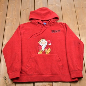 May include: Red hooded sweatshirt featuring a cartoon image of Grumpy from Snow White and the Seven Dwarfs. The text "GRUMPY" is printed on the sweatshirt.