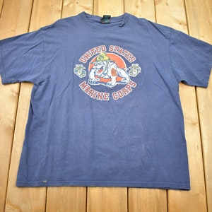 May include: A blue t-shirt with a graphic of a bulldog wearing a military hat and the text "United States Marine Corps".
