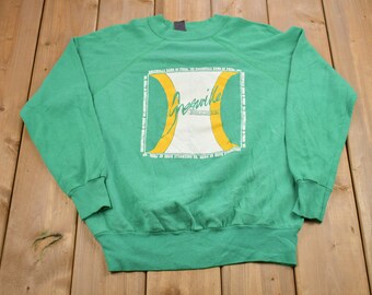 Puede incluir: Sudadera verde con un logotipo amarillo y blanco que dice "Greenville" con el texto "The Greenville Band of Friends" repetido alrededor del logotipo.
