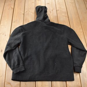 May include: A black fleece zip-up hoodie with a high collar.