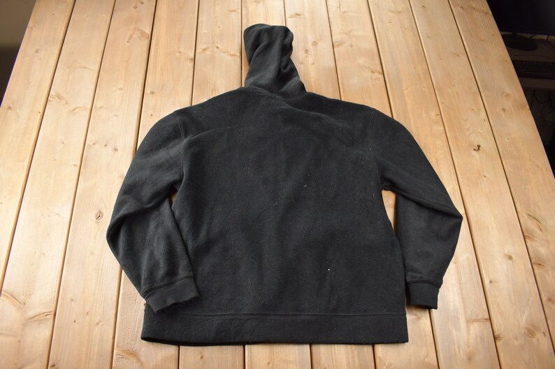 May include: A black fleece zip-up hoodie with a high collar.