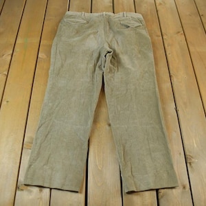 Może przedstawiać: Spodnie z brązowego, cienkiego materiału typu „kord”. Spodnie mają prosty krój nogawek i luźny fason.