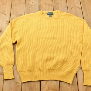 May include: A yellow ribbed knit sweater with a crew neck.