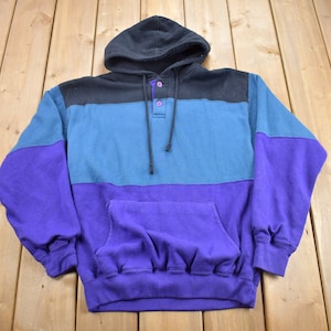 May include: A purple, blue and black striped hooded sweatshirt with a single button closure at the neck.