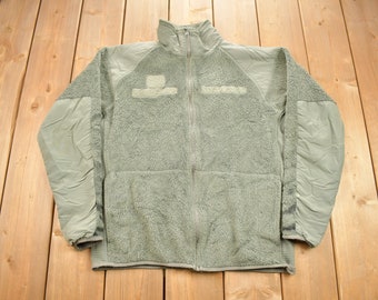 May include: A green fleece jacket with a zipper closure and two pockets. The jacket has a high collar and is made of a soft, warm material.