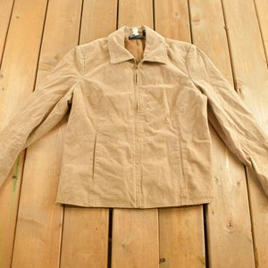 May include: A tan corduroy jacket with a zipper closure and long sleeves.