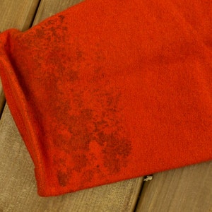 K&ouml;nnte beinhalten: Nahaufnahme eines leuchtend orangenen Stoffes mit einem braunen Fleck. Der Stoff hat eine flauschige Textur.