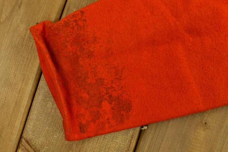 K&ouml;nnte beinhalten: Nahaufnahme eines leuchtend orangenen Stoffes mit einem braunen Fleck. Der Stoff hat eine flauschige Textur.