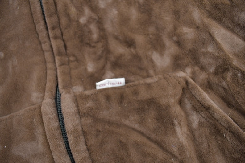 May include: A brown fleece jacket with a zipper closure and a Carhartt label on the pocket.