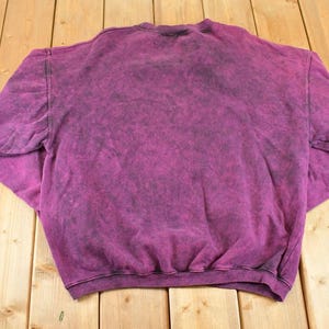 May include: A long-sleeve crewneck sweatshirt featuring a deep magenta and black acid-wash pattern. The garment has a ribbed collar, ribbed cuffs, and a ribbed hemline, showcasing a mottled, uneven color distribution across the entire fabric surface.