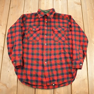 May include: Red and black plaid flannel shirt with long sleeves and button closure.