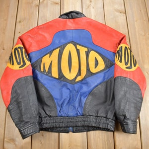 May include: A black, red, blue and yellow leather jacket with the word "MOJO" printed on the back.