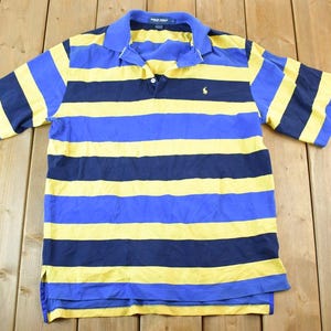 May include: A blue and yellow striped polo shirt with a small embroidered logo on the left chest.