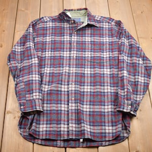 May include: A long-sleeved plaid shirt with a button-up front. The shirt is made of a soft, flannel-like material and features a red, blue, and white plaid pattern.