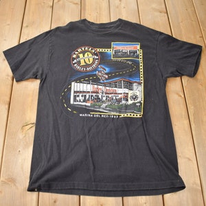 May include: Black t-shirt with a graphic of a Harley-Davidson dealership and the text "Bartels 10 Harley-Davidson Marina Del Rey 1993".