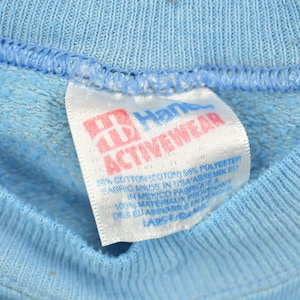 May include: A white Hanes Activewear tag with pink lettering. The tag states "60% cotton 40% polyester, fabric made in USA, assembled in Mexico, fabrique a 100% materiaux provenant des EU, assemble en Mexique, LARC 31544".