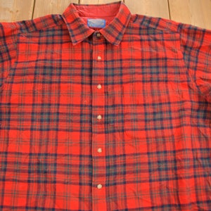 Puede incluir: Camisa de franela a cuadros rojos y negros con cierre de botones.