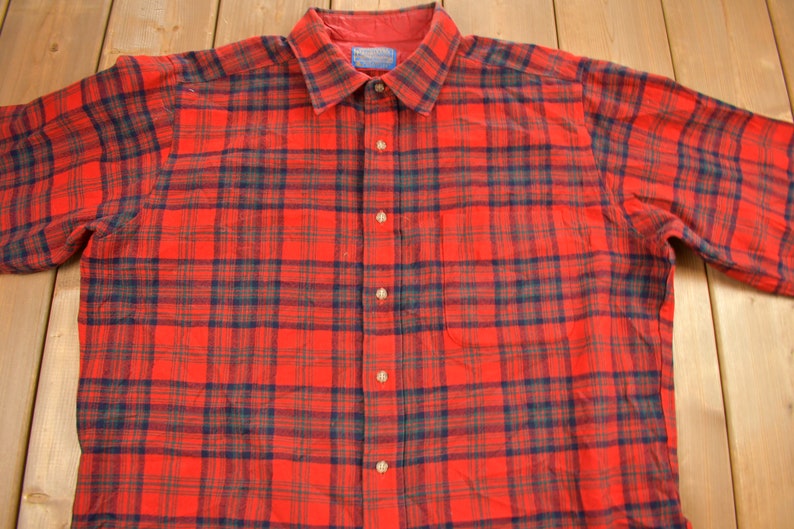 Puede incluir: Camisa de franela a cuadros rojos y negros con cierre de botones.