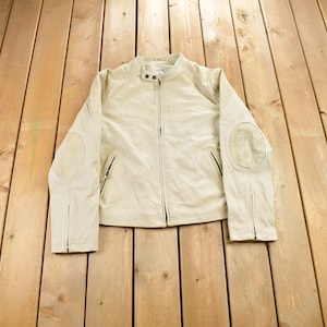 May include: A cream-coloured leather jacket with a zip fastening and suede elbow patches.
