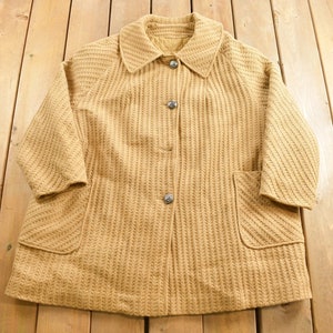 May include: A brown, knitted, long-sleeved coat with a collar and four buttons down the front. The coat has two pockets on the front.