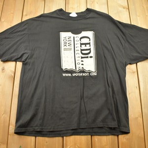 May include: Black t-shirt with a white graphic of a ticket that says "CEDI! COLLECTION NEW YORK" and "www.spotdetroit.com".