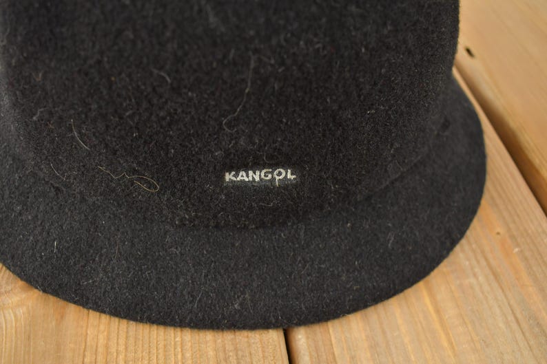 May include: Black felt bucket hat with a Kangol logo.