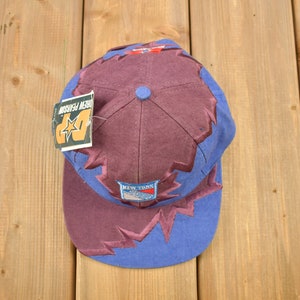 May include: A purple and blue baseball cap with a New York Rangers logo and a "Urban Season" tag. The cap has a lightning bolt design.