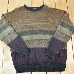 Könnte beinhalten: Ein Vintage-Pullover mit Rundhalsausschnitt und horizontalen Streifen in Braun-, Grün- und Lilatönen. Die Ärmel und der untere Saum sind dunkler Lila. Der Pullover ist aus einem strukturierten Strickstoff gefertigt.