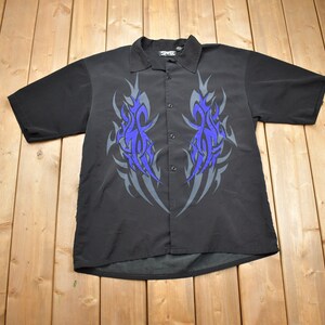 May include: A black short-sleeved button-down shirt with a tribal print in shades of blue and gray.