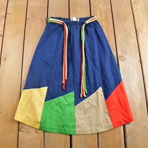 May include: A blue, yellow, green and red patchwork skirt with a colourful drawstring waist.