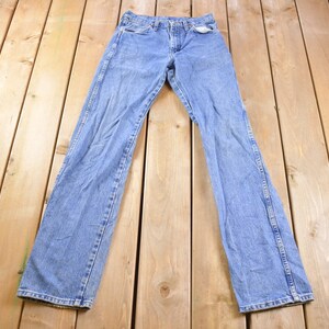 May include: A pair of light blue denim jeans laid flat on a wooden surface.