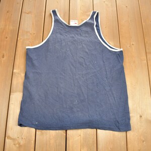 May include: A plain blue sleeveless shirt with a white trim around the neck and armholes.