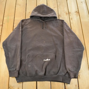 May include: A dark gray hooded sweatshirt with a front pocket and drawstring. The Carhartt logo is visible on the front pocket. The sweatshirt is made of a thick, durable material.