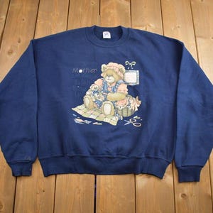 May include: A navy blue sweatshirt with a graphic of a teddy bear holding a smaller teddy bear. The graphic includes the text "Mother, you are always in my heart, I love you more than words can say".