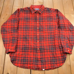 Puede incluir: Una camisa de manga larga a cuadros rojos y negros con cierre de botones.