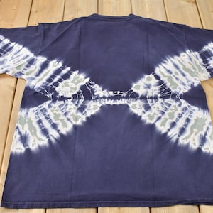 May include: A navy blue tie-dye t-shirt with white and light blue patterns. The shirt has a crew neck and short sleeves.