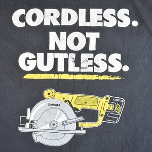 May include: Black t-shirt with white text that reads "Cordless. Not Gutless." and a yellow and black illustration of a DeWalt circular saw.