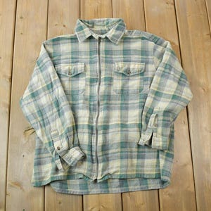 May include: A long-sleeved plaid shirt with a zip closure. The shirt is a light blue and green plaid pattern.