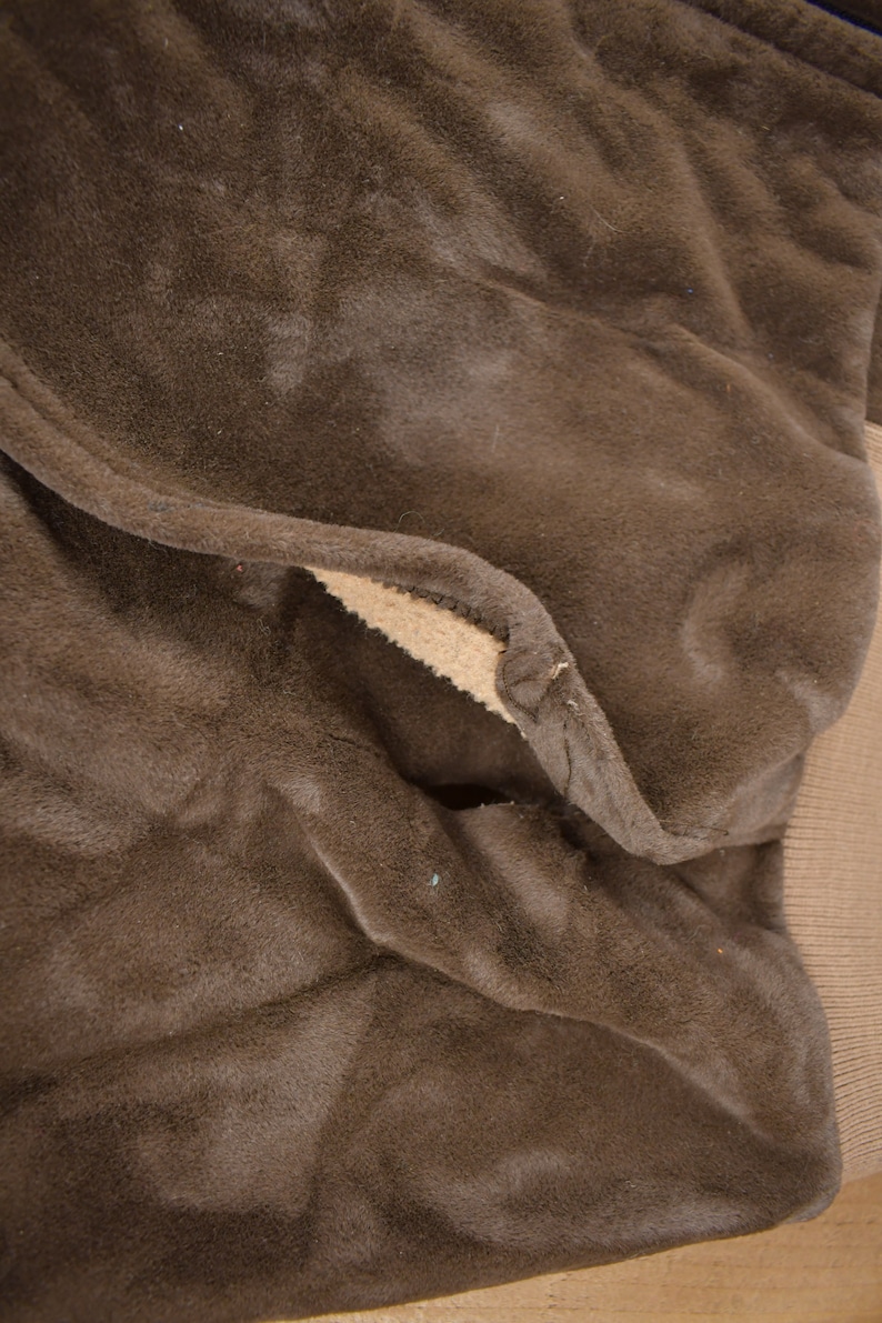 May include: Close-up of the brown fleece lining of a jacket. The fleece is soft and plush, and the seams are visible.