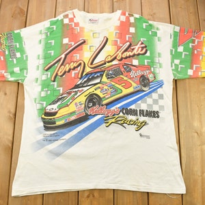 Può includere: Maglietta bianca con una stampa colorata di un'auto da corsa, il nome del pilota "Terry Labonte" e il testo "Kellogg's Corn Flakes Racing".
