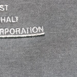 Puede incluir: Primer plano de una tela gris con texto bordado en blanco. El texto dice "MIDWEST ASPHALT CORPORATION" en una fuente estilizada. La tela tiene una apariencia texturizada.