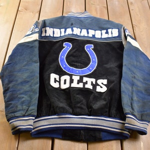 Op de afbeelding: Een blauwe en zwarte vintage Indianapolis Colts jas met een groot hoefijzerlogo en het woord "COLTS" in witte letters.