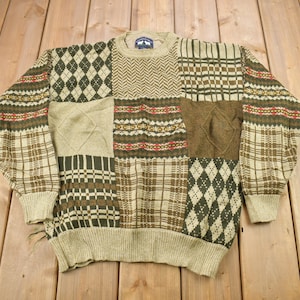 May include: A beige and brown patchwork sweater with a variety of patterns, including plaid, diamond, and herringbone.