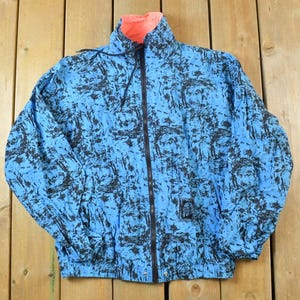 May include: A blue and black patterned jacket with a zip closure. The jacket has a pink lining.