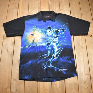 May include: A black and blue short-sleeved button-up shirt with a graphic print of a blue, glowing figure with a sun behind it. The shirt has the text "Rock Star" printed on the bottom right corner.