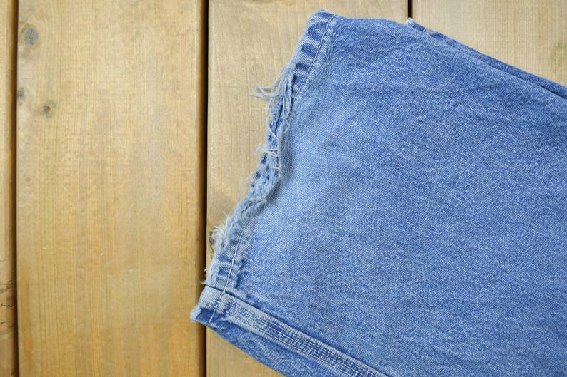 May include: A close-up of the frayed edge of a pair of blue denim jeans.