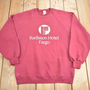 May include: A maroon sweatshirt with a white logo that says "Radisson Hotel Fargo" and a stylized "F" in a circle.