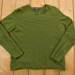 May include: A dark green long-sleeved sweater with a crew neck.